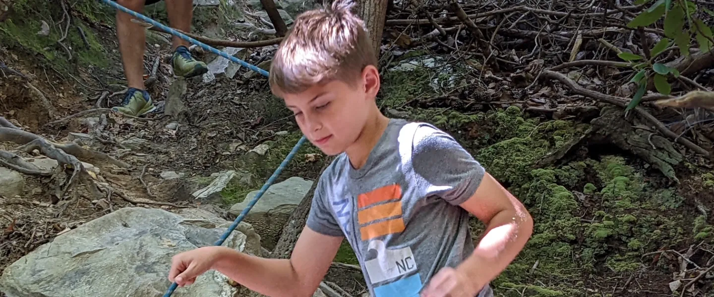 Kid climbing down hidden cliffs