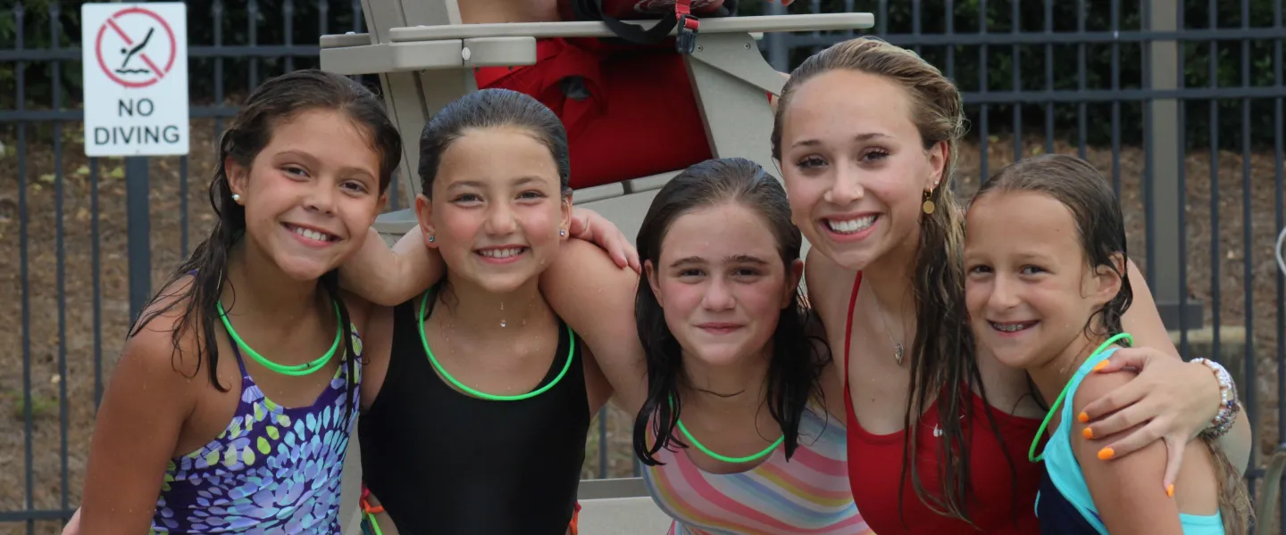 5 girls standing wet by the pool