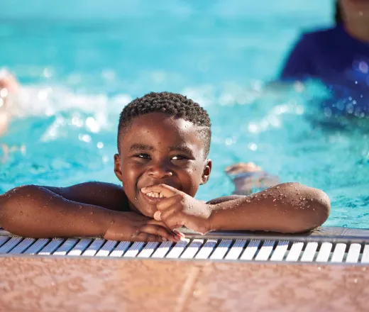 Boy smiling on the side of the pool